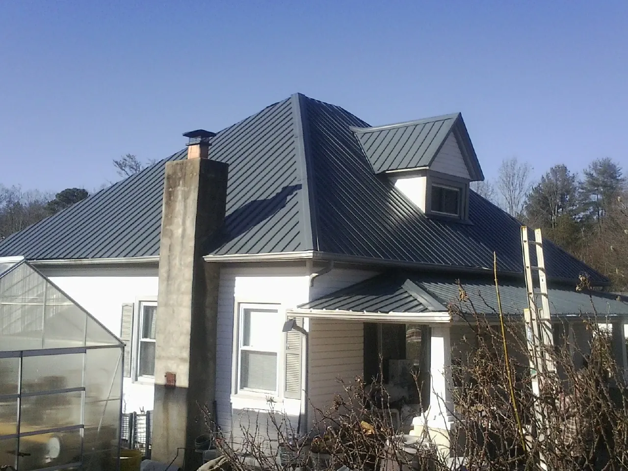 Dark blue standing seam metal roof on a white farmhouse with dormer — Slate & Tile Roof Repair by Roofing Brothers in West Jordan