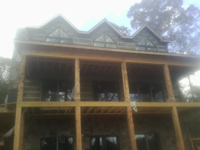 Dormers and porch framing on a large log home under construction — Roof Coating work by our crew in West Jordan