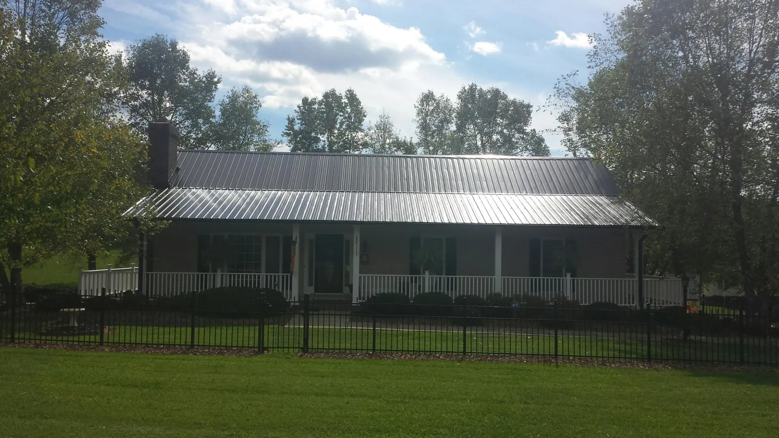 Gray metal roof on a brick ranch with a full width front porch — Gutter Guard Installation work by our crew in West Jordan