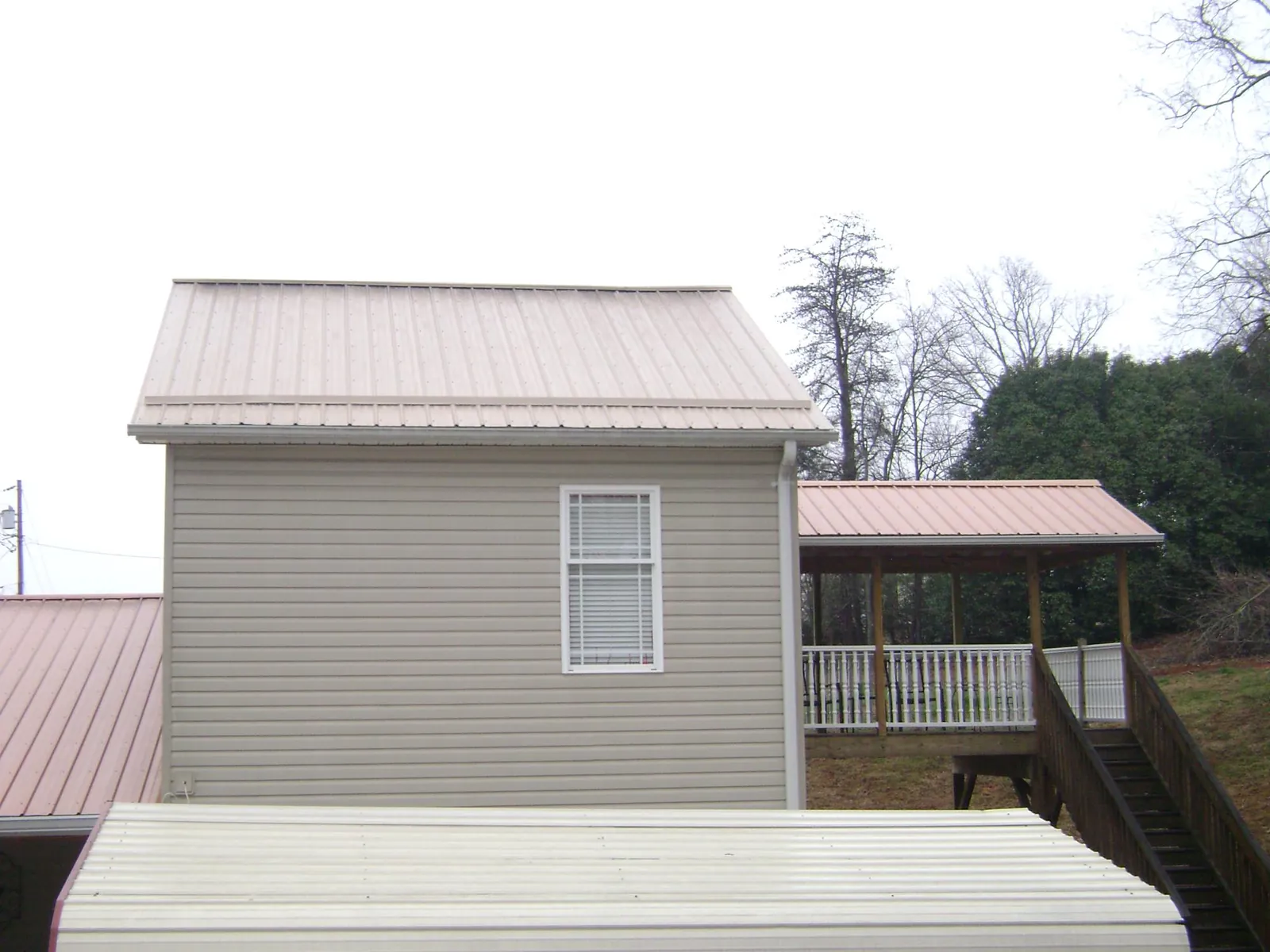 Tan metal roofs on a two story addition and attached porch, from a Roof Replacement job in West Jordan