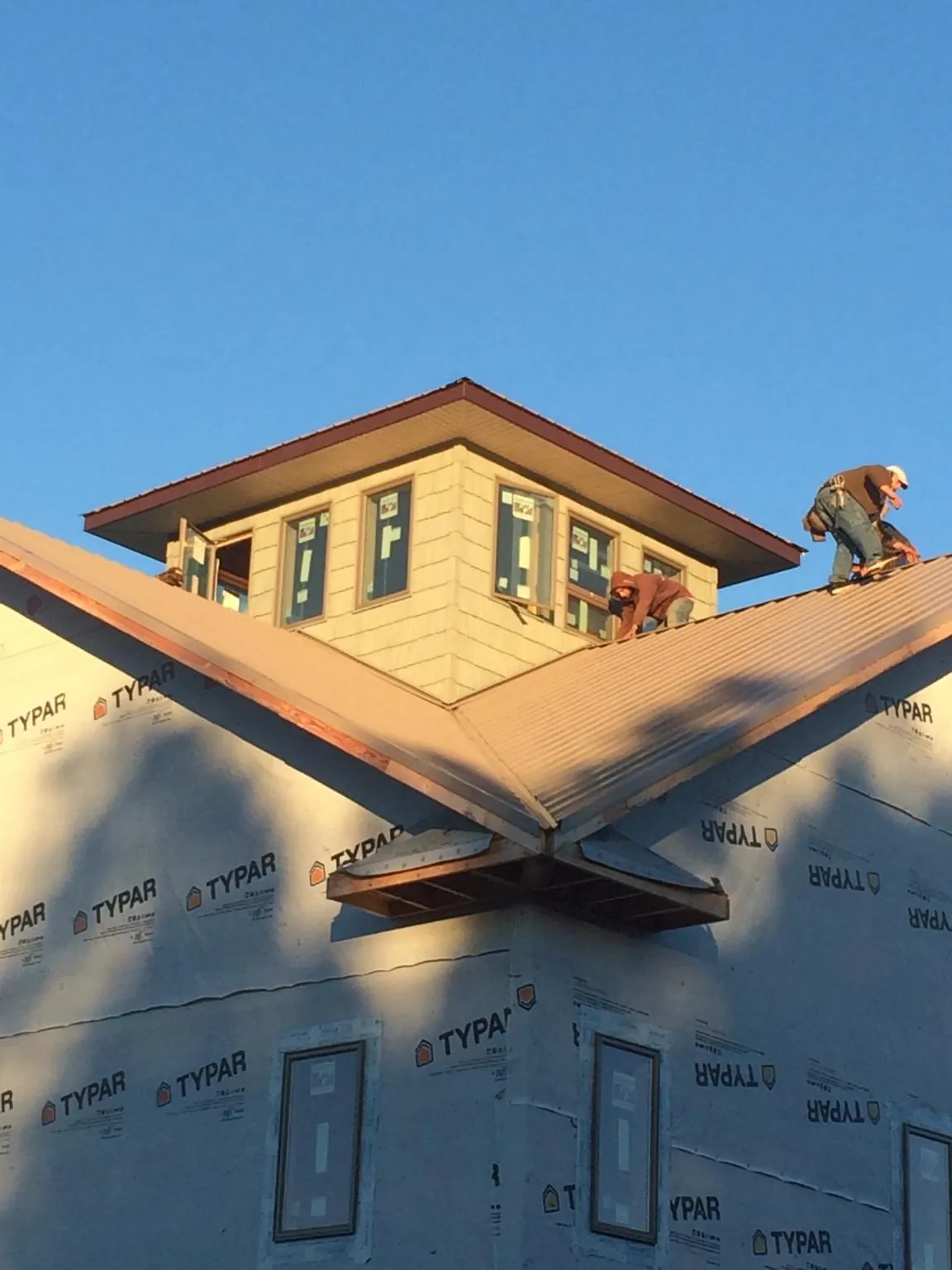 Roofers working around a rooftop cupola on a new metal roof at sunset — Roof Waterproofing in West Jordan by Roofing Brothers